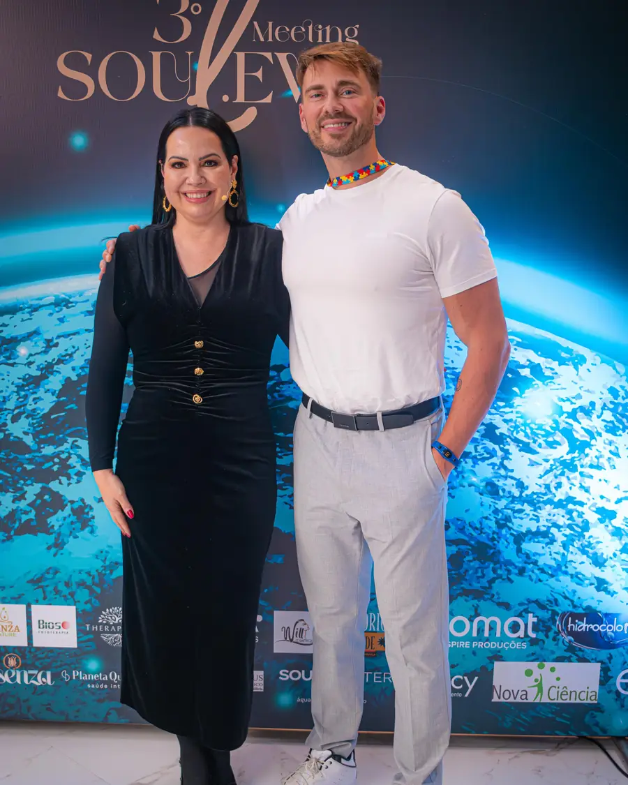 Sara ao lado de um convidado no backdrop do 3º Soul Meeting